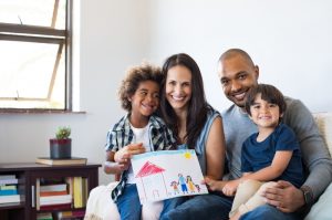 family-sits-on-couch-with-child's-drawing